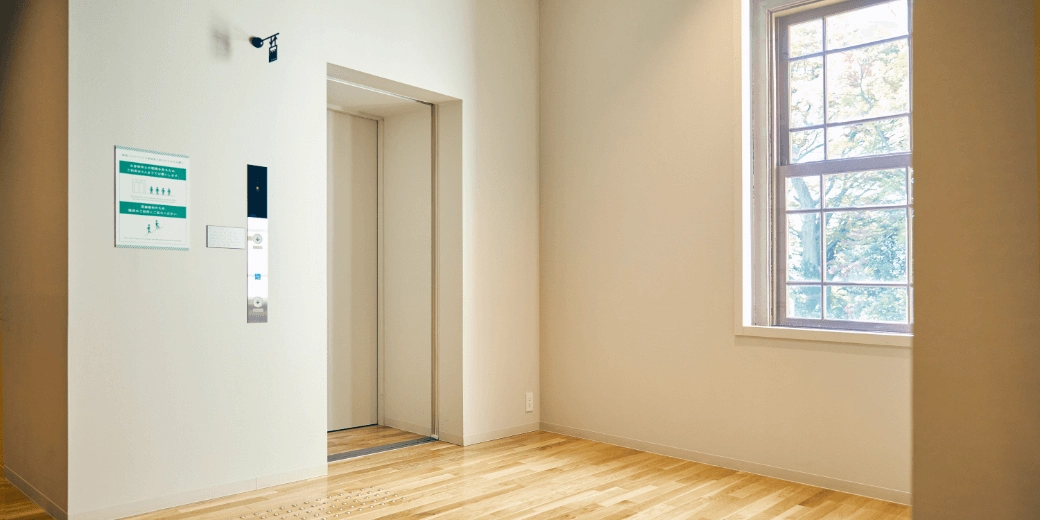 Photo : One white elevator door. There is an operation button on the left side.