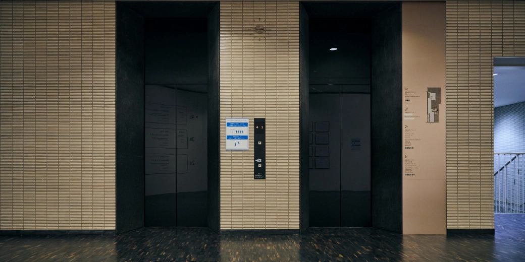 Photo : Elevator with two black doors side by side. There is an operation button in the middle.