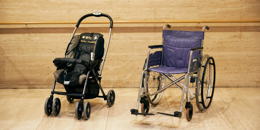 Photo : A simple black stroller and a wheelchair with a purple seat lined up