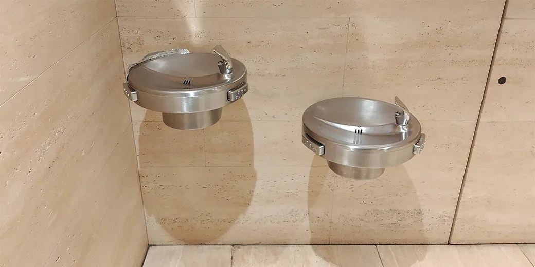 Photo : In the back, there is a window with curtains and four chairs for children, a simple sink in front of it, a white adult chair next to it, and a folding diaper-changing seat in front.